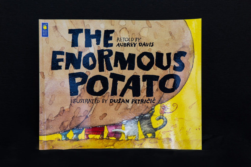 The Enormous Potato book cover. Many animated characters lifting a big potato