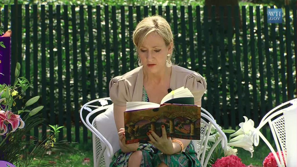 photo of J.J. Rowling reading one of her books in a garden