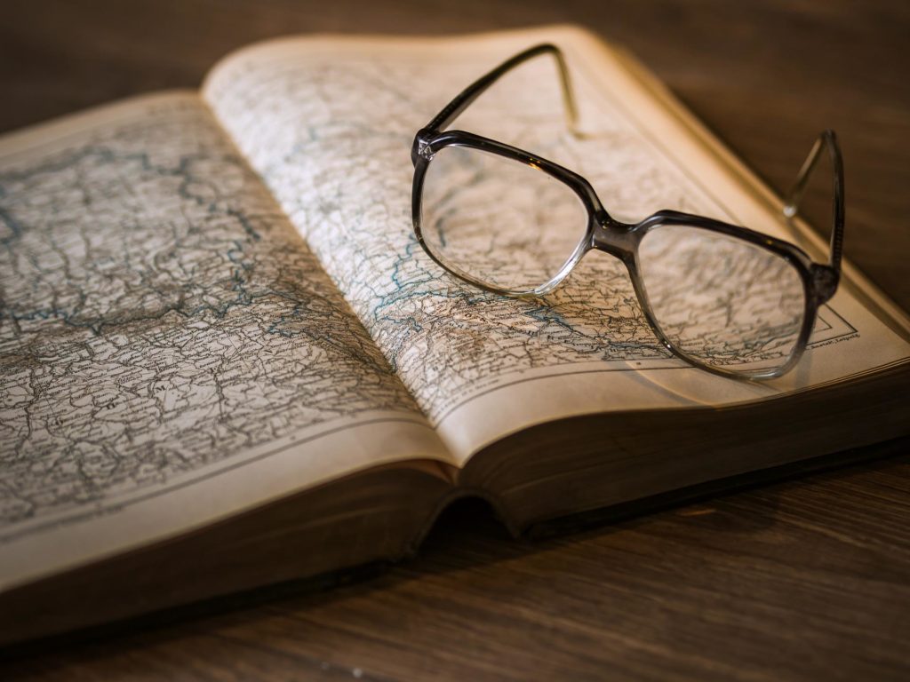 glasses sitting on a book of maps